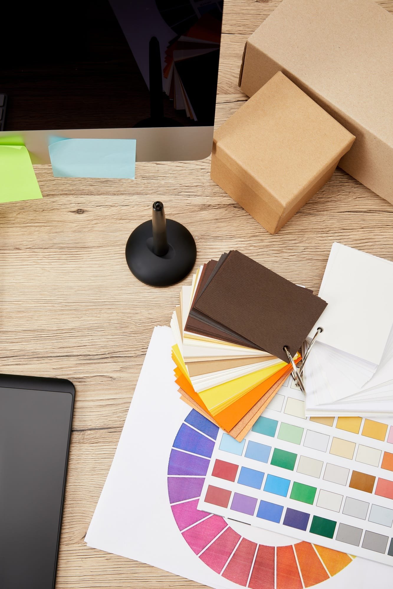 top view of graphic designer workplace with arranged computer screen, colorful stickers, graphic